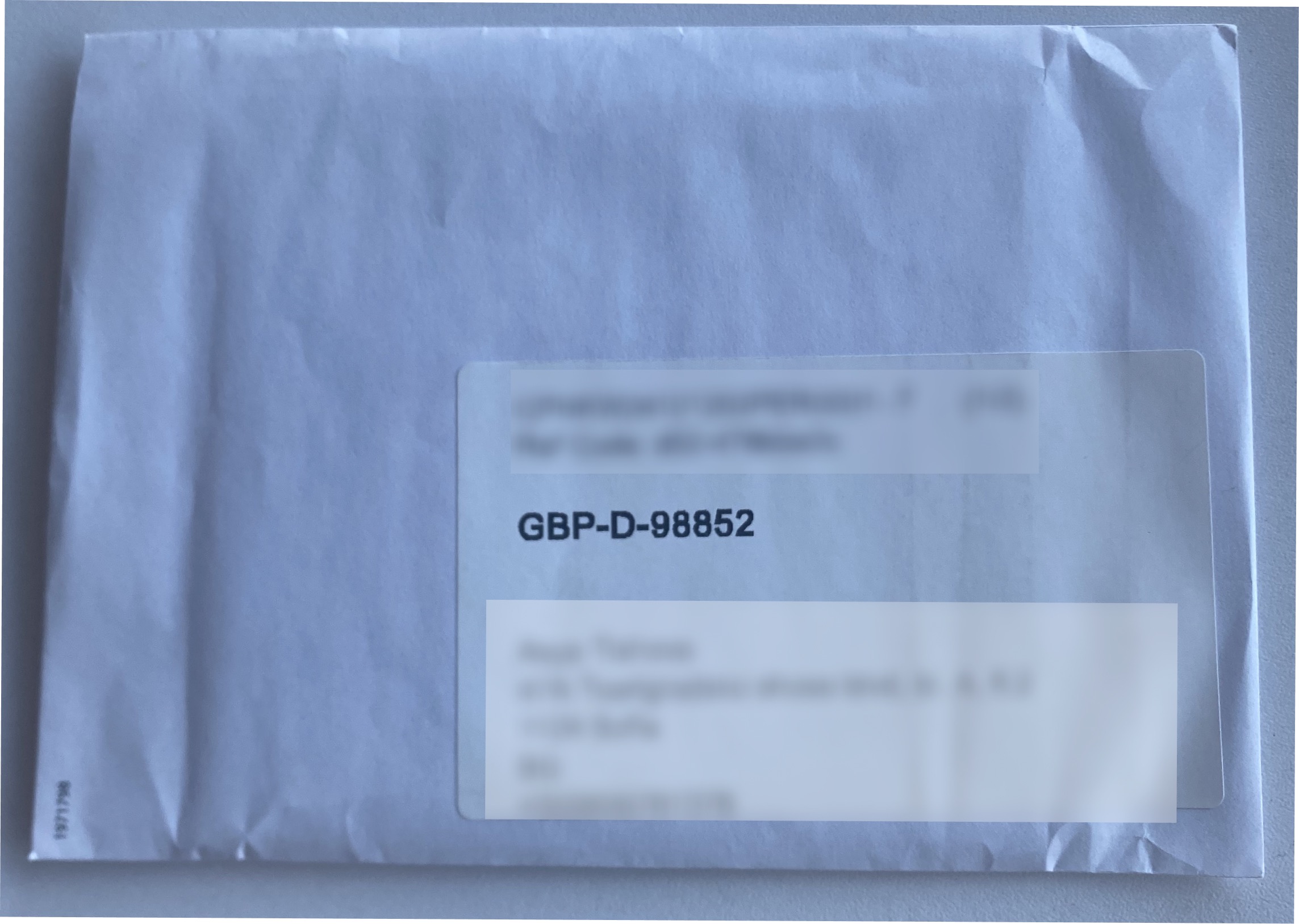 A pre-order card envelope with the assignment code GBP-D-98852 shown in the address window.